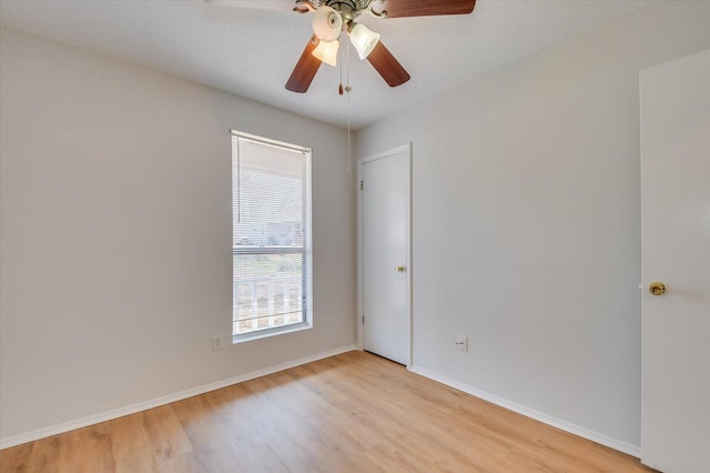 unfurnished room with ceiling fan, light wood-style flooring, and baseboards