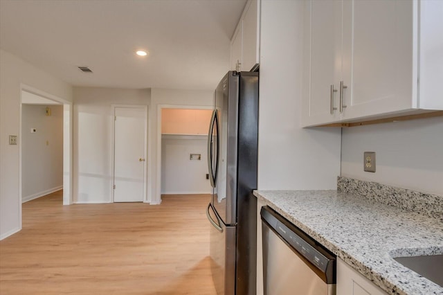 kitchen with stainless steel appliances, light wood finished floors, white cabinetry, and light stone counters