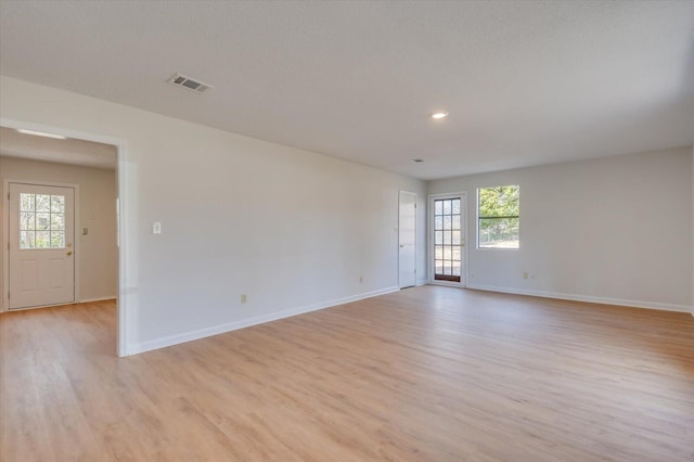 spare room with a wealth of natural light, visible vents, light wood-style flooring, and baseboards