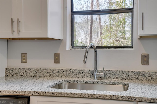 kitchen featuring a wealth of natural light, white cabinets, and a sink