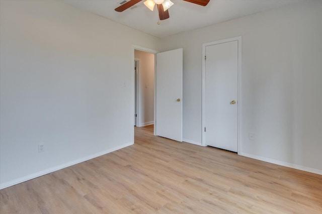 spare room with wood finished floors, a ceiling fan, and baseboards