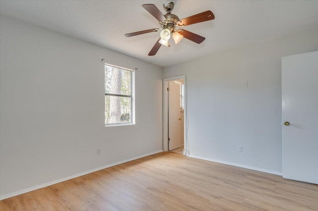 spare room featuring light wood-style floors, baseboards, and a ceiling fan