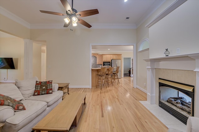 972 Woody Hill Cir, Evans, GA 30809 - living area featuring a ceiling fan, light wood-style flooring, ornamental molding, a tiled fireplace, and baseboards