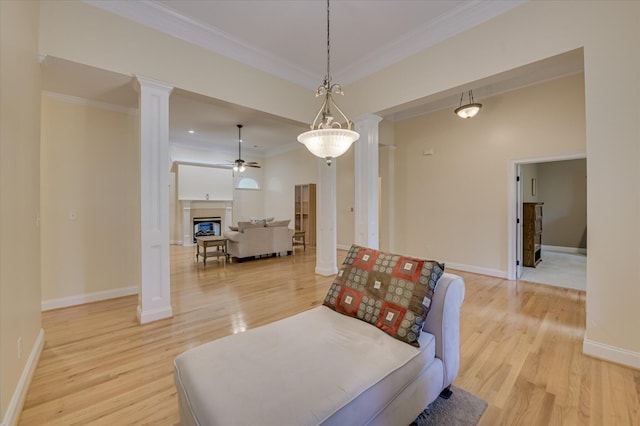 972 Woody Hill Cir, Evans, GA 30809 - sitting room featuring ornate columns, light wood-style flooring, crown molding, a ceiling fan, and a glass covered fireplace