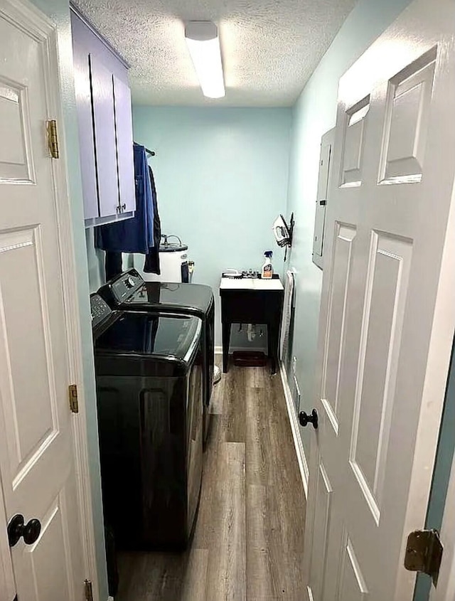 washroom with a textured ceiling, washing machine and dryer, baseboards, cabinet space, and dark wood-type flooring