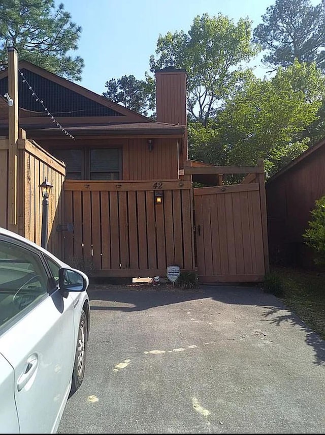 exterior space featuring fence, a chimney, and a gate