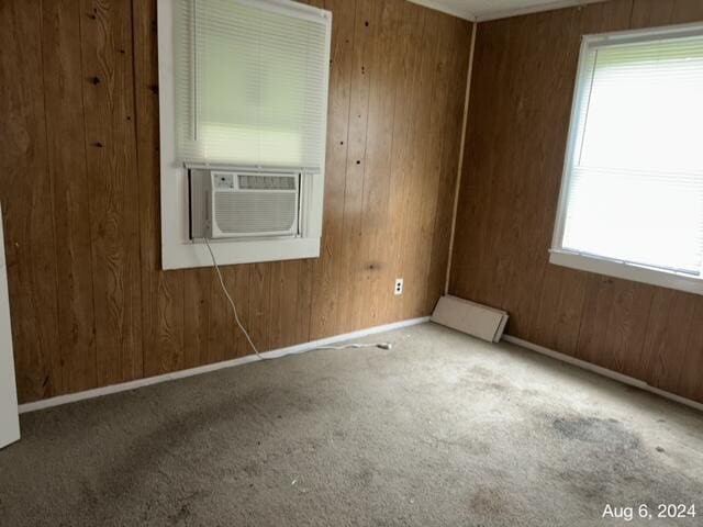 carpeted empty room with cooling unit and wooden walls