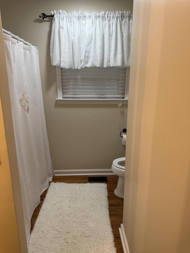 410 Johns Rd, Thomson, GA 30824 - bathroom with toilet, wood finished floors, baseboards, and a shower with shower curtain