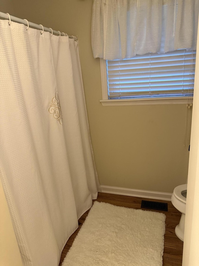 410 Johns Rd, Thomson, GA 30824 - full bathroom with wood finished floors, toilet, baseboards, and a shower with shower curtain