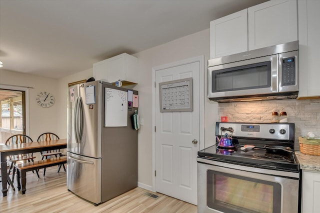 2107 Brown Rd, Hephzibah, GA 30815 - kitchen with light wood finished floors, light stone countertops, decorative backsplash, white cabinets, and stainless steel appliances
