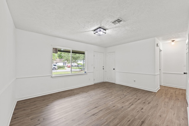 spare room with a textured ceiling and light hardwood / wood-style flooring