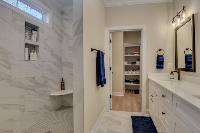 bathroom featuring vanity, ornamental molding, and tiled shower