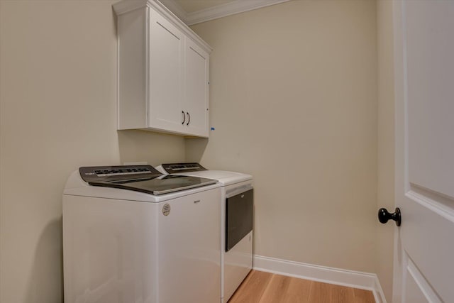 washroom featuring washer and dryer, cabinets, crown molding, and light hardwood / wood-style flooring