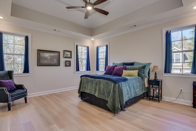 bedroom with a raised ceiling, multiple windows, and ceiling fan