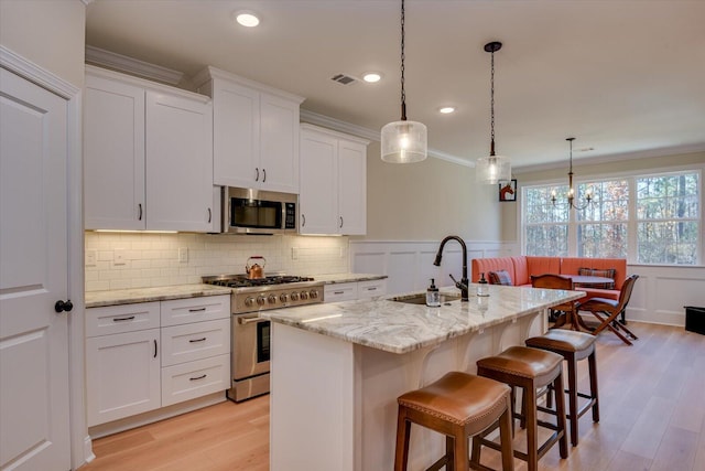 kitchen with a center island with sink, white cabinets, stainless steel appliances, and sink