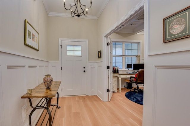 entryway with light hardwood / wood-style floors, ornamental molding, and an inviting chandelier