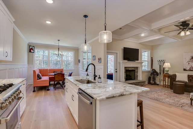 kitchen with a kitchen island with sink, white cabinetry, sink, and appliances with stainless steel finishes