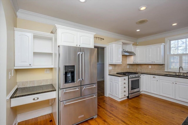 kitchen with a sink, white cabinets, premium appliances, and wood finished floors