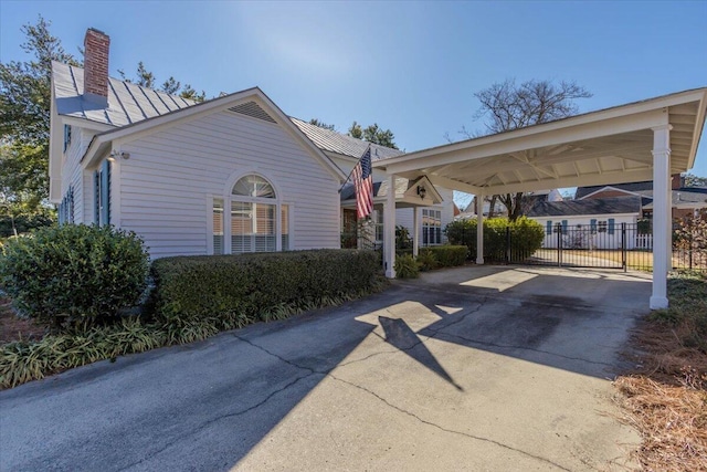 exterior space featuring a carport, a chimney, fence, and driveway