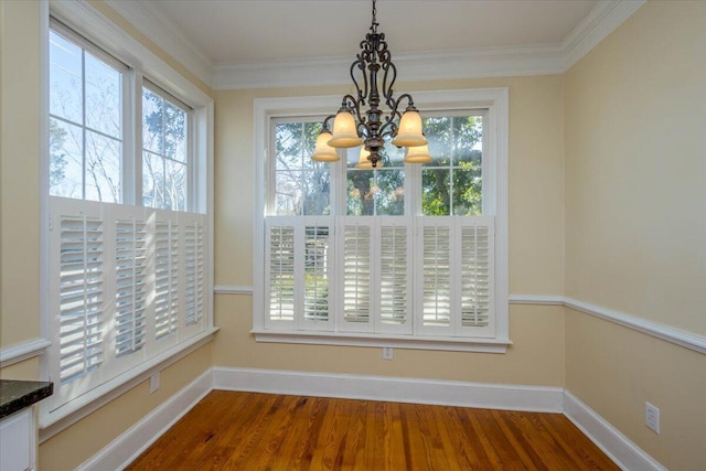 unfurnished dining area with an inviting chandelier, baseboards, dark wood finished floors, and ornamental molding