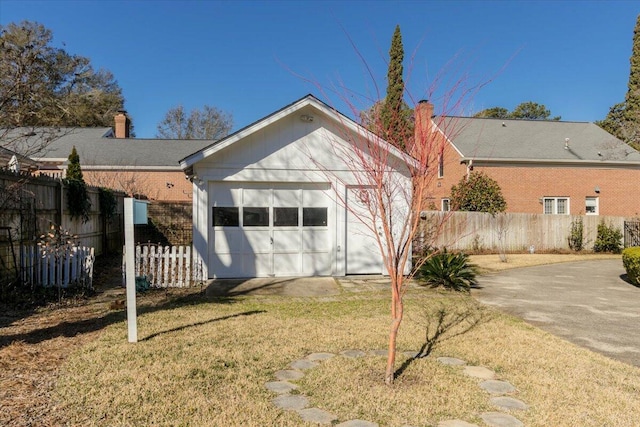 back of house featuring brick siding, a yard, a chimney, fence, and a garage