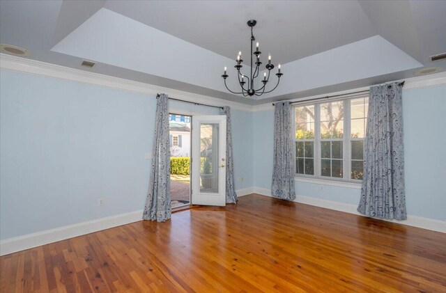 unfurnished room featuring a tray ceiling, wood finished floors, and baseboards