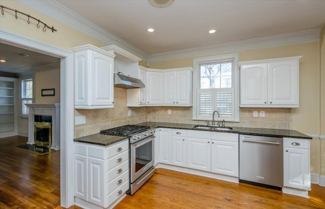 kitchen with appliances with stainless steel finishes, a sink, white cabinets, and under cabinet range hood