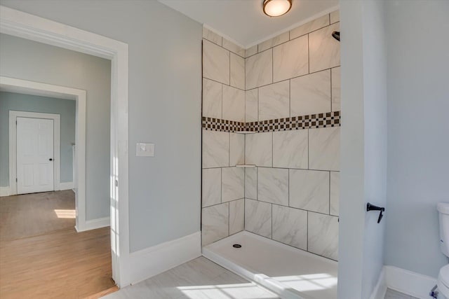 bathroom featuring toilet, tile patterned flooring, and a tile shower