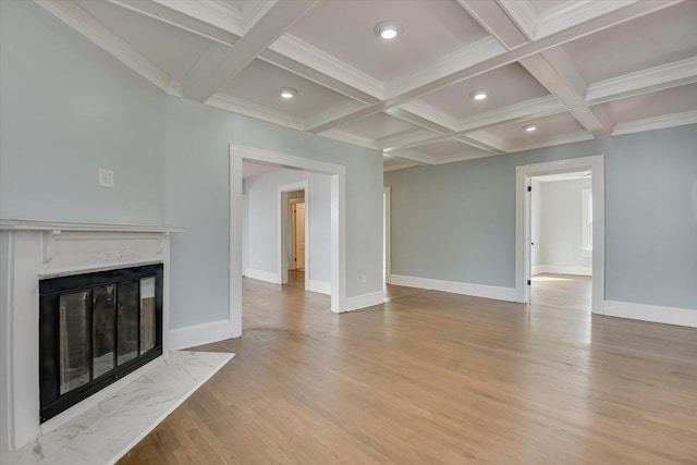 unfurnished living room featuring coffered ceiling, light wood-type flooring, a fireplace, ornamental molding, and beamed ceiling