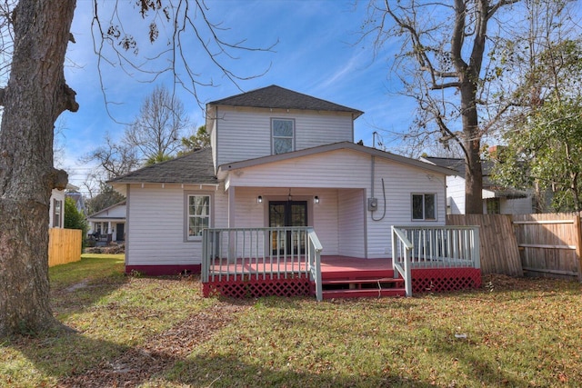 back of property with a deck and a yard