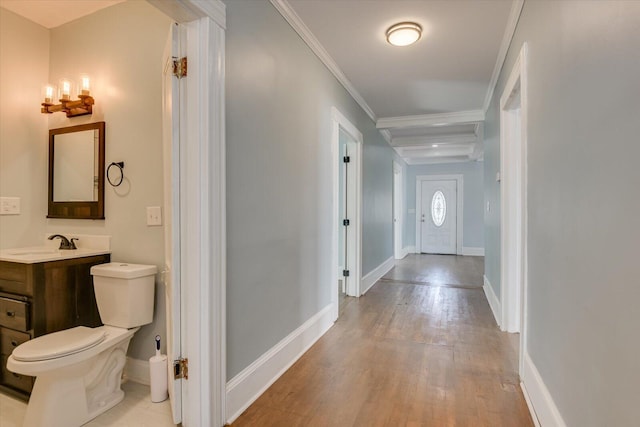 hall with light wood-type flooring, crown molding, and sink