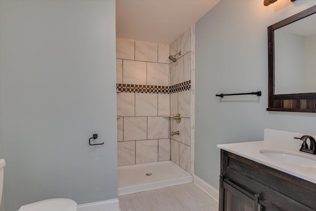 bathroom featuring toilet, tile patterned flooring, tiled shower, and vanity