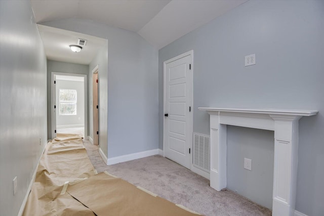 hall featuring lofted ceiling and light colored carpet