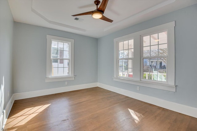 unfurnished room with a raised ceiling, ceiling fan, and hardwood / wood-style flooring