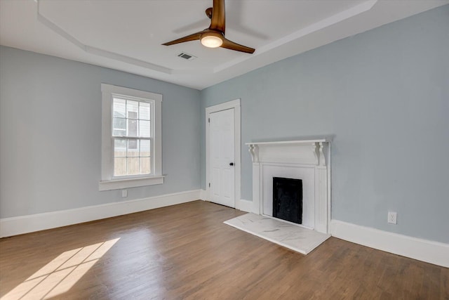 unfurnished living room with ceiling fan, hardwood / wood-style floors, and a raised ceiling