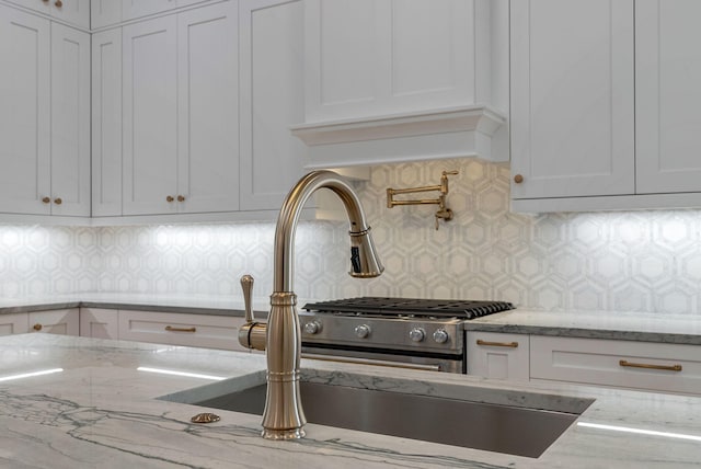 kitchen featuring decorative backsplash, light stone counters, and white cabinetry