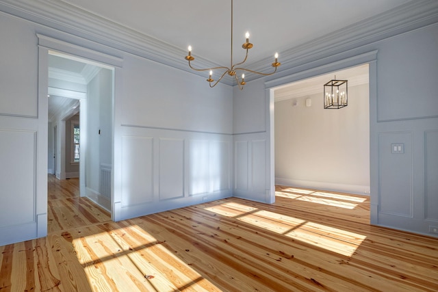 spare room featuring light hardwood / wood-style flooring, a notable chandelier, and crown molding