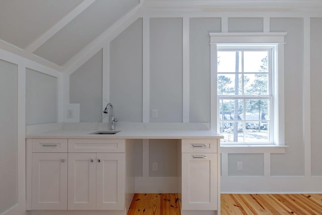 interior space featuring white cabinets, light wood-type flooring, light stone countertops, and sink