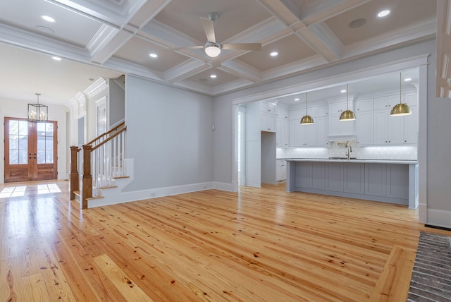 unfurnished living room with french doors, light wood-type flooring, coffered ceiling, and beam ceiling