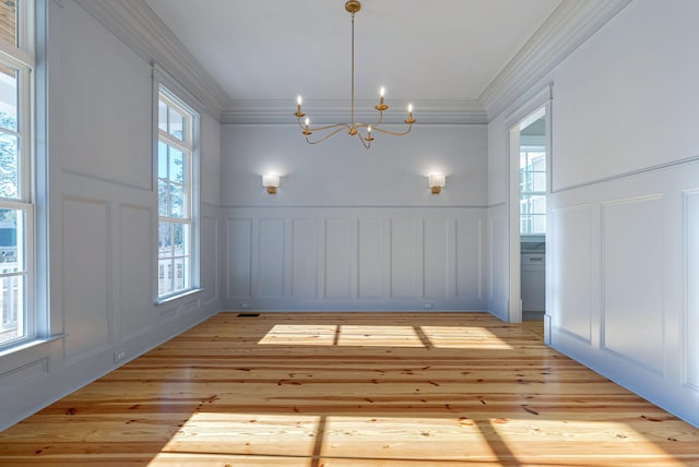 unfurnished dining area featuring crown molding, light hardwood / wood-style flooring, and an inviting chandelier