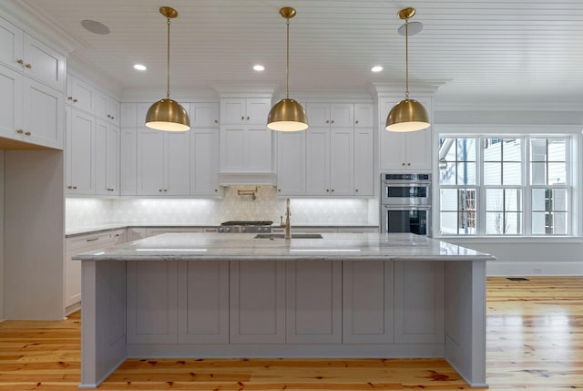 kitchen with light hardwood / wood-style flooring, light stone counters, double oven, and sink