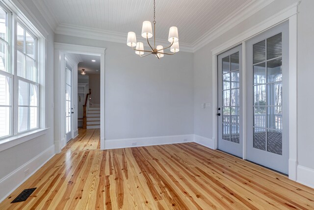 empty room featuring crown molding, a chandelier, and light wood-type flooring