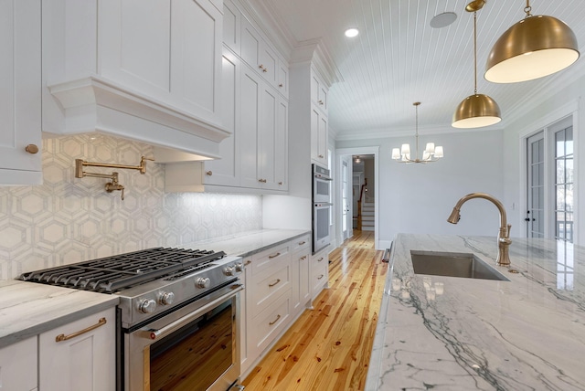 kitchen featuring light stone countertops, tasteful backsplash, stainless steel appliances, white cabinets, and hanging light fixtures