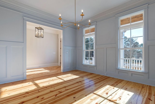 unfurnished dining area with a notable chandelier, ornamental molding, and light hardwood / wood-style flooring