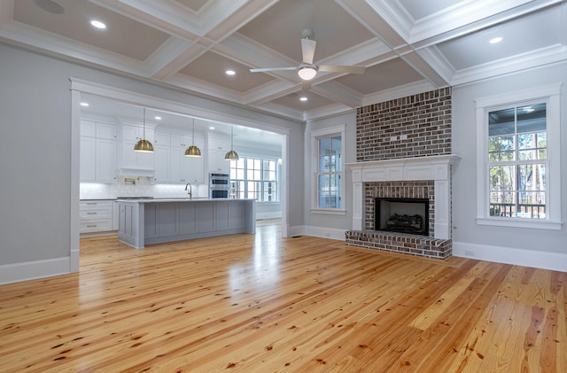 unfurnished living room with beamed ceiling, light wood-type flooring, a fireplace, and coffered ceiling