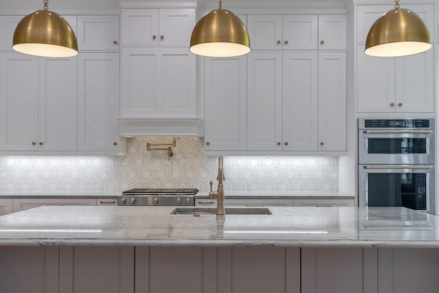 kitchen with tasteful backsplash, light stone countertops, white cabinets, and decorative light fixtures