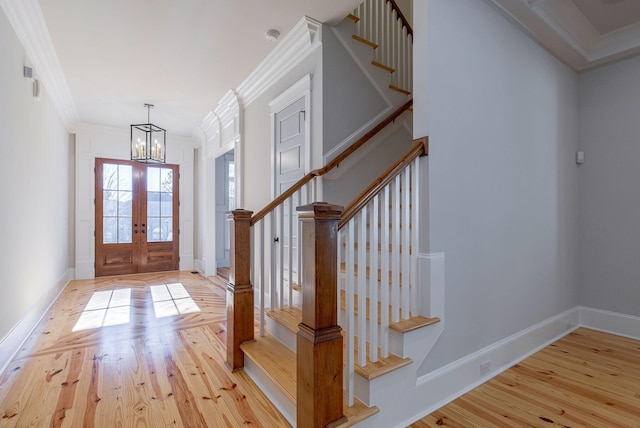 foyer entrance with french doors, an inviting chandelier, light hardwood / wood-style flooring, and ornamental molding