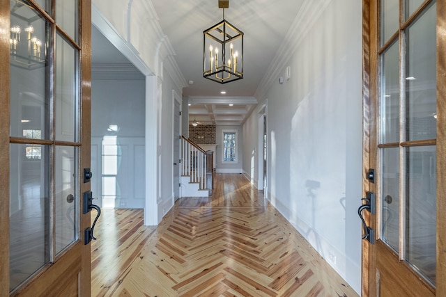 foyer featuring coffered ceiling, light parquet floors, crown molding, a notable chandelier, and beamed ceiling