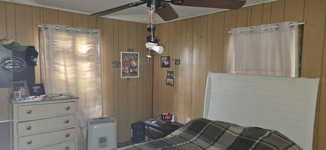 bedroom featuring wooden walls, crown molding, and ceiling fan