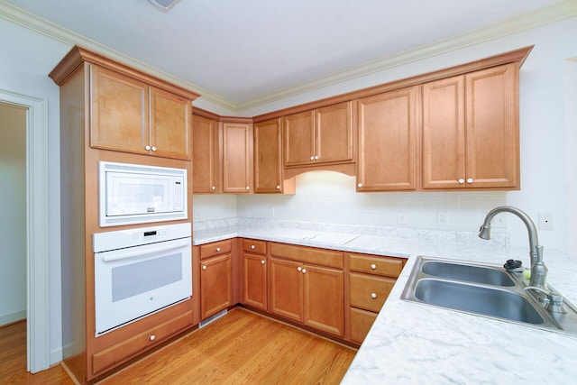 kitchen featuring sink, light wood-type flooring, decorative backsplash, ornamental molding, and white appliances